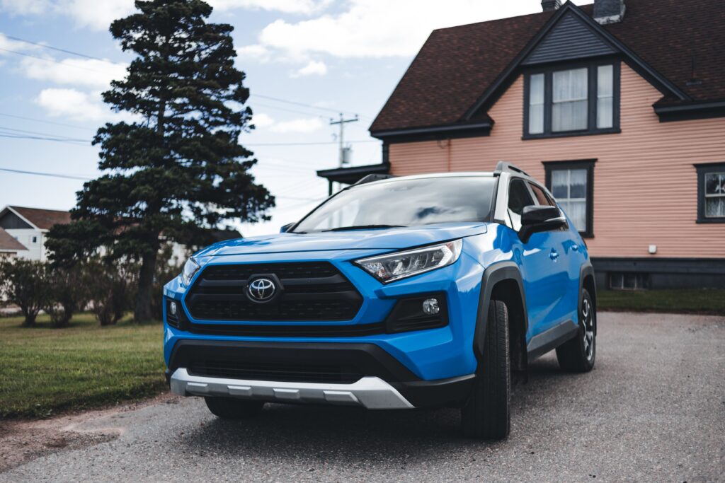 A blue suv parked in front of a pink house.